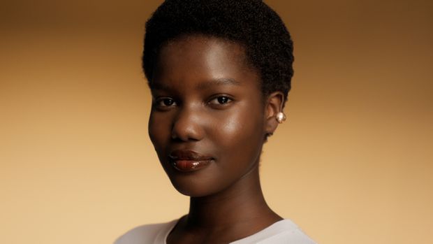 Model with coily hair after applying Dyson Amino scalp care.