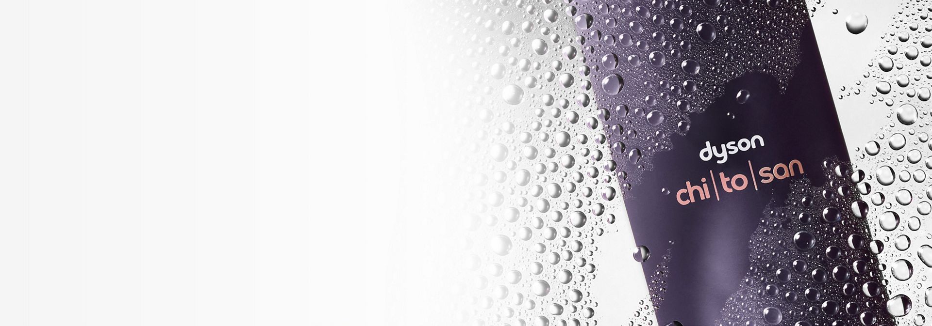 Dyson Chitosan Multi-use styling spray behind water droplets on a glass pane.
