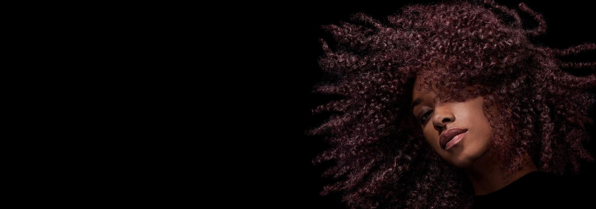 Model with voluminous brown coily hair styled with Dyson Chitosan products.