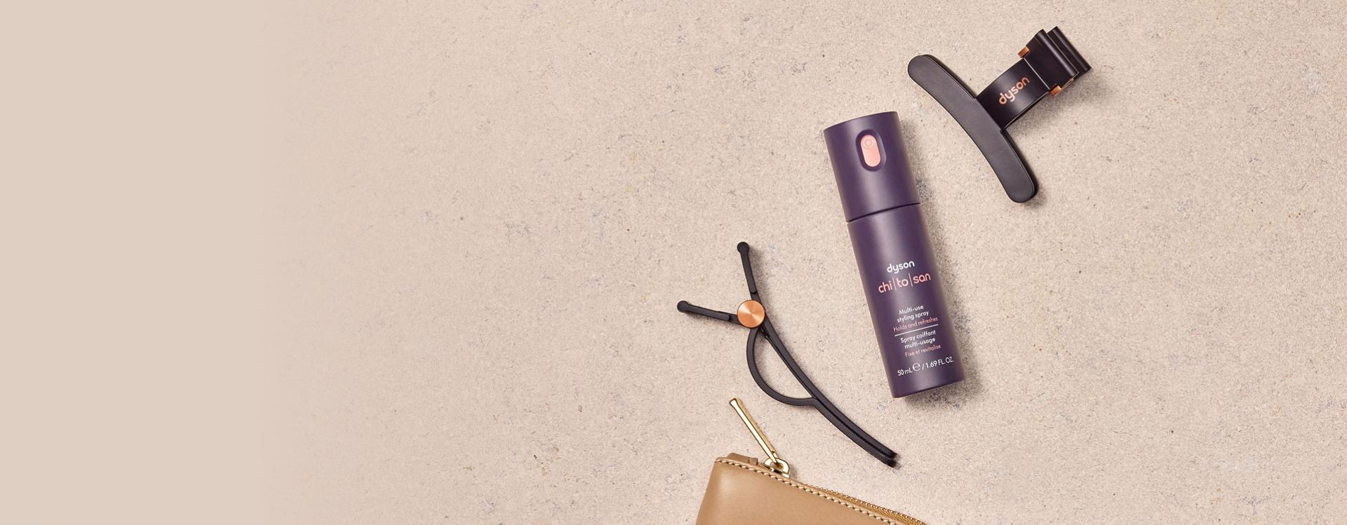 The Dyson Chitosan Multi-use styling spray travel mini with a set of Dyson hair clips.