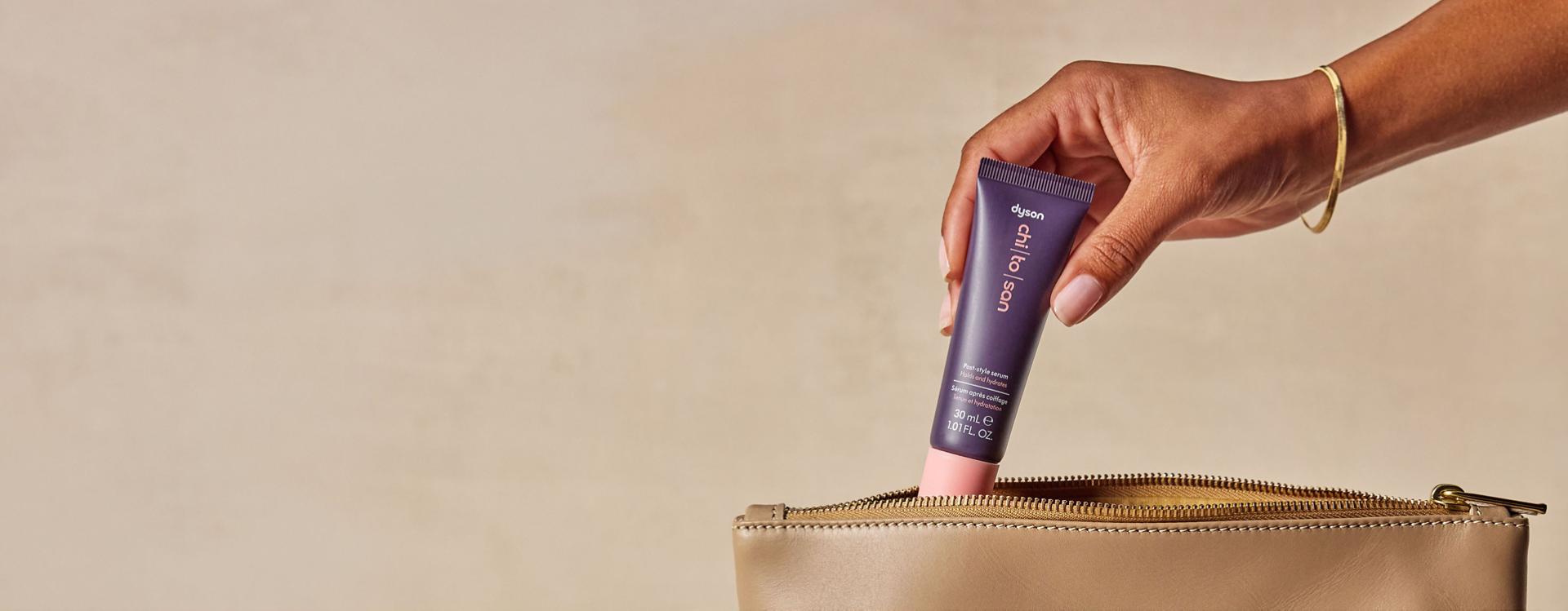 Dyson Chitosan Post-style serum travel mini retrieved from a toiletries bag.