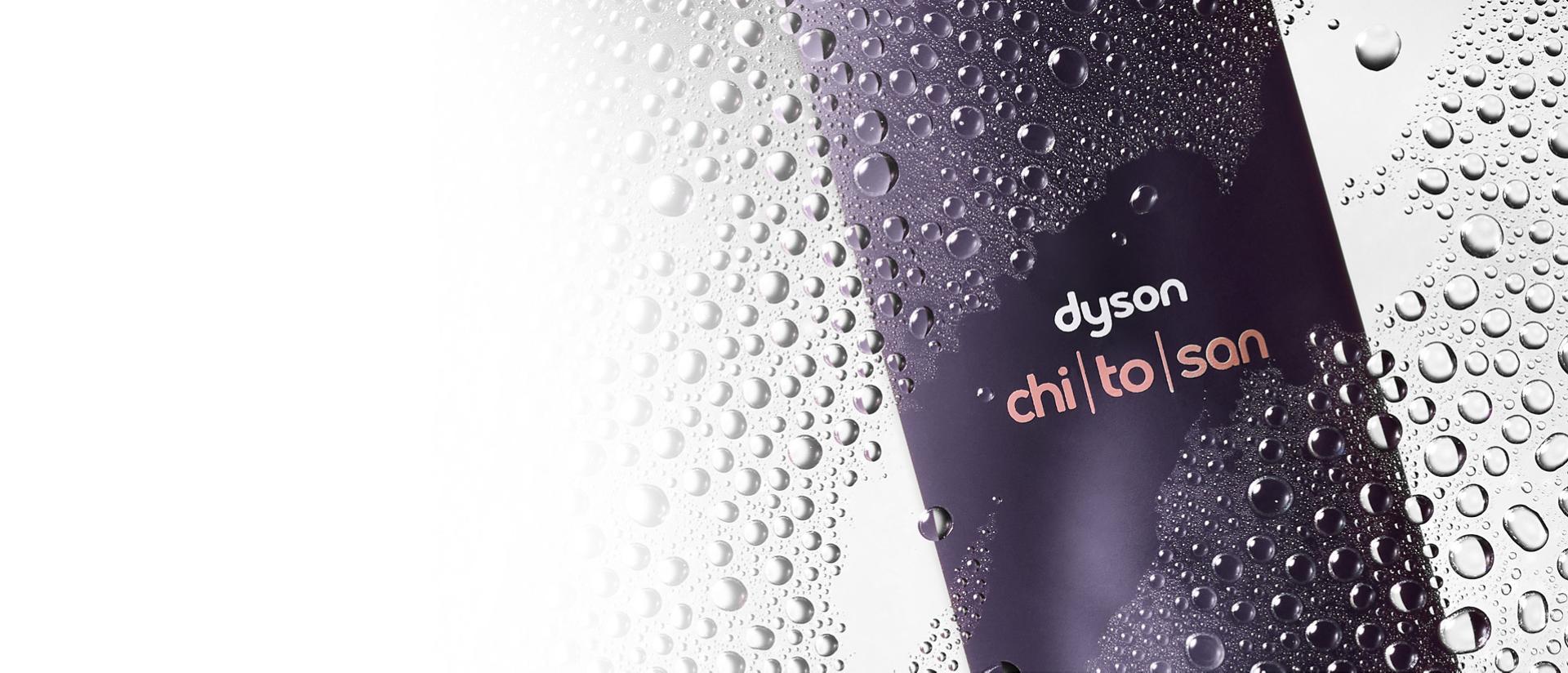 Dyson Chitosan Multi-use styling spray behind water droplets on a glass pane.