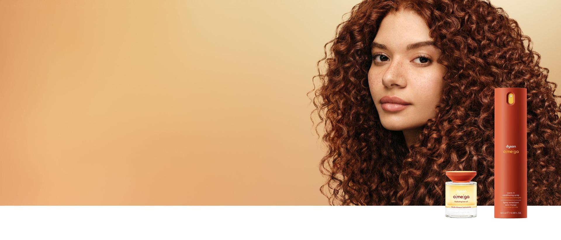 A curly haired model behind the Dyson Omega hair care range.