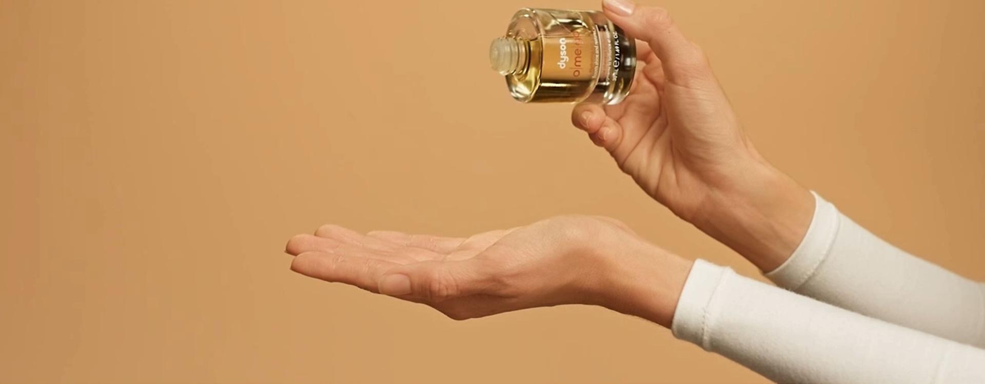 Dyson Omega hydrating hair oil is dropped into a hand.