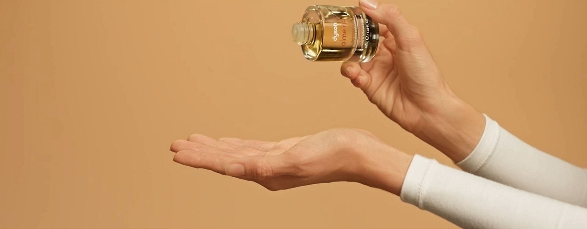 Dyson Omega hydrating hair oil is dropped into a hand.