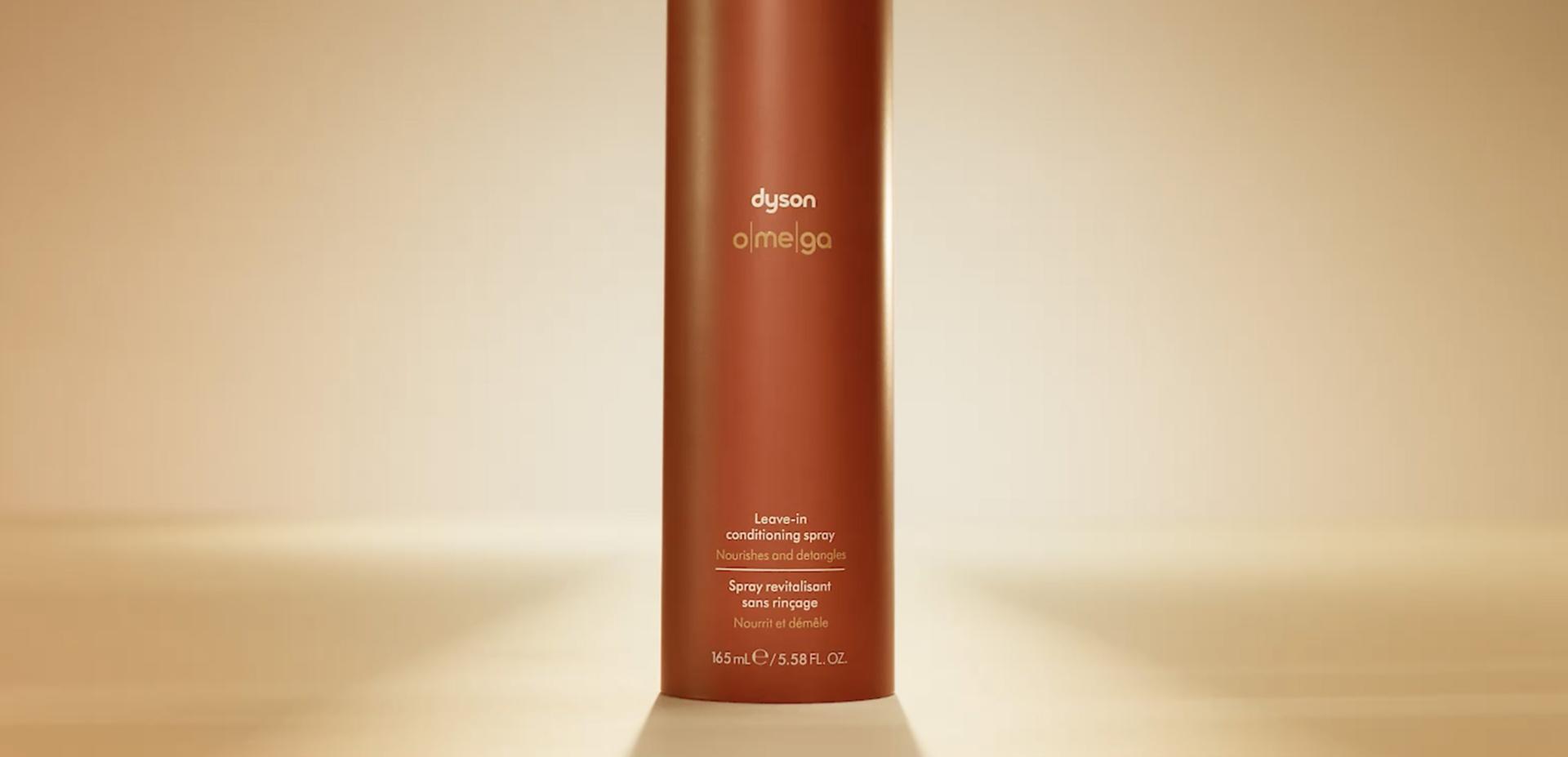 The Dyson Omega leave-in conditioning spray illuminated from behind with a warm glow.