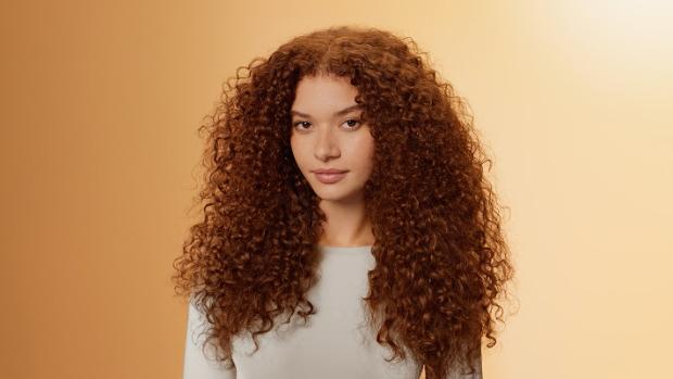 Modelka o naturalnie kręconych włosach, pielęgnowanych produktami z serii Dyson Omega.