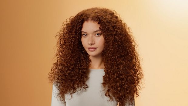 Modelka o naturalnie kręconych włosach, pielęgnowanych produktami z serii Dyson Omega.