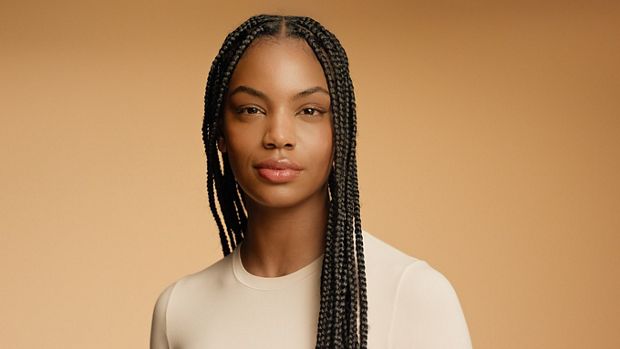 Modelka o naturalnie kręconych włosach, ułożonych w fryzurę ochronną i odżywionej produktami z serii Dyson Omega.