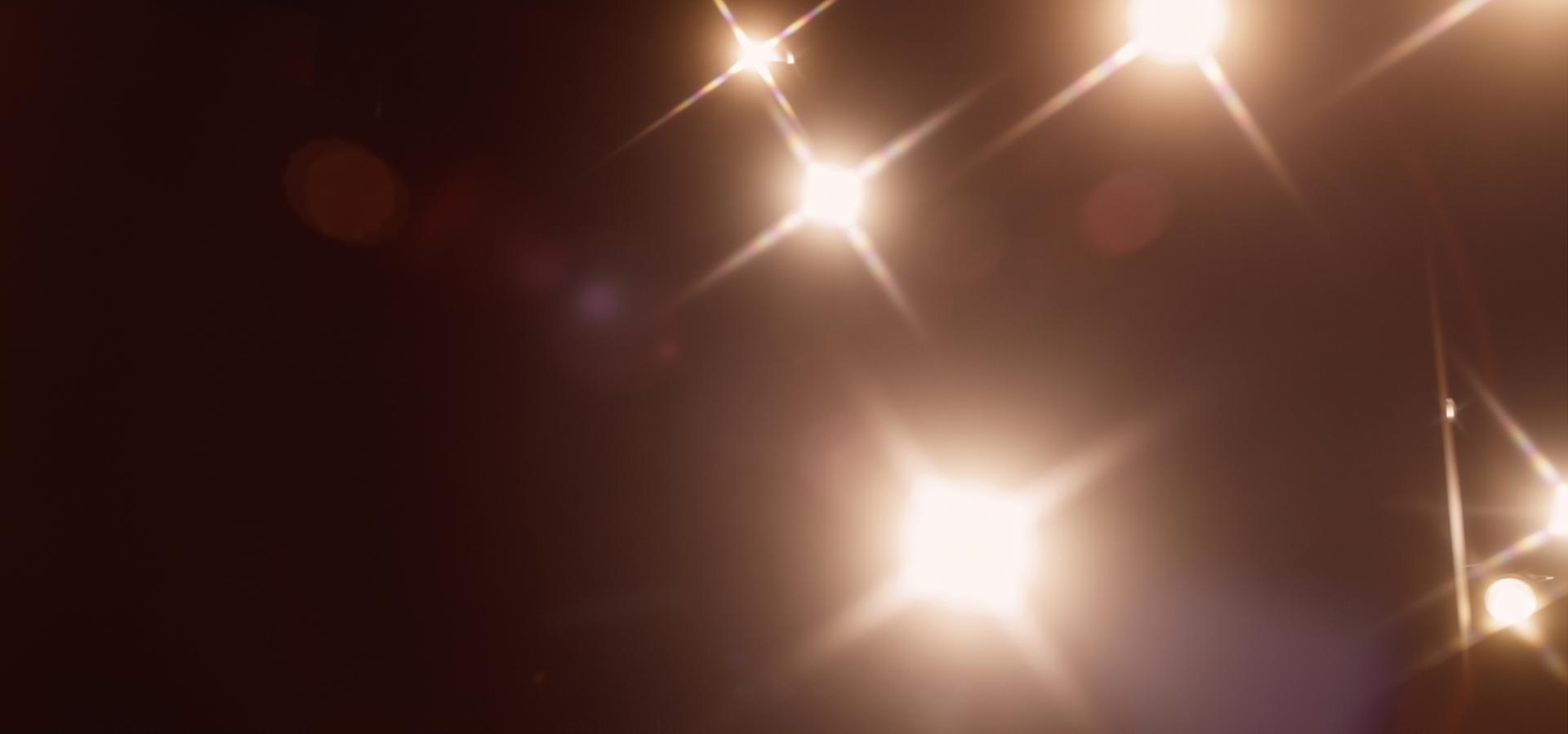 Glimmering lights with lens flares on a dark background.