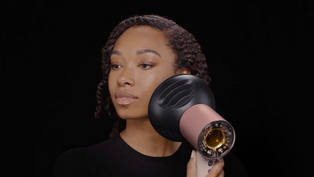 A model dries her hair with the Dyson Supersonic Nural hair dryer.