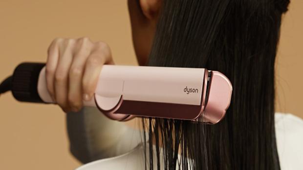 A model dries and straightens her hair with the Dyson Airstrait dryer and straightener.