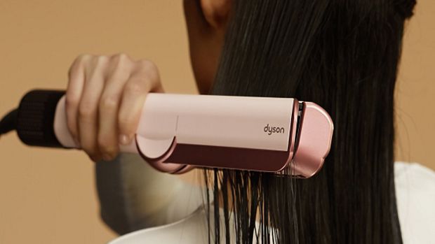 A model dries and straightens her hair with the Dyson Airstrait dryer and straightener.