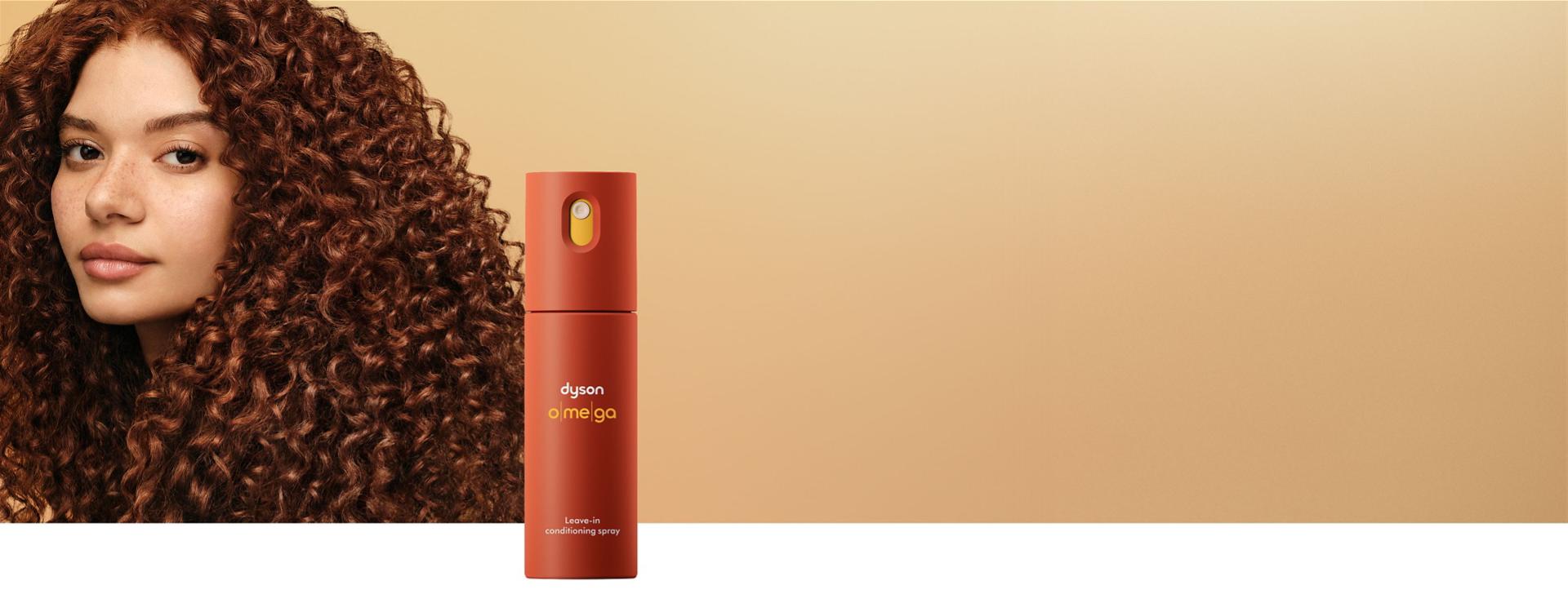 Modelka s vyživenými vlasy s bezoplachovým kondicionérem ve spreji Dyson Omega v popředí.