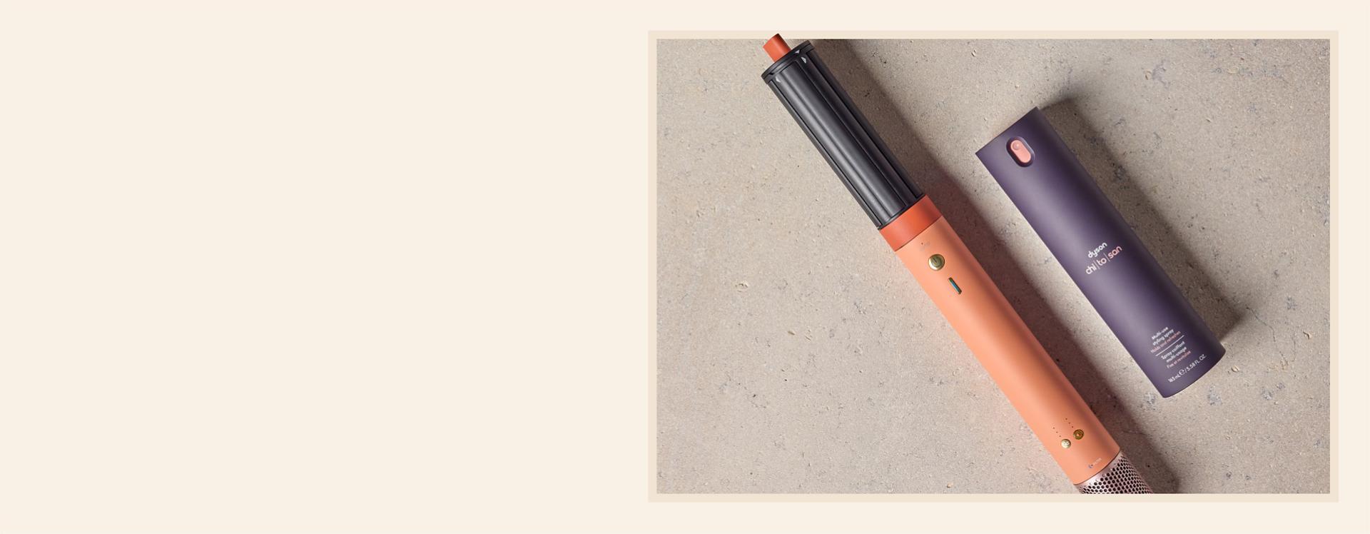 Dyson Airwrap Co-anda2x multi-styler and dryer with Dyson Chitosan Multi-use styling spray on a stony background.