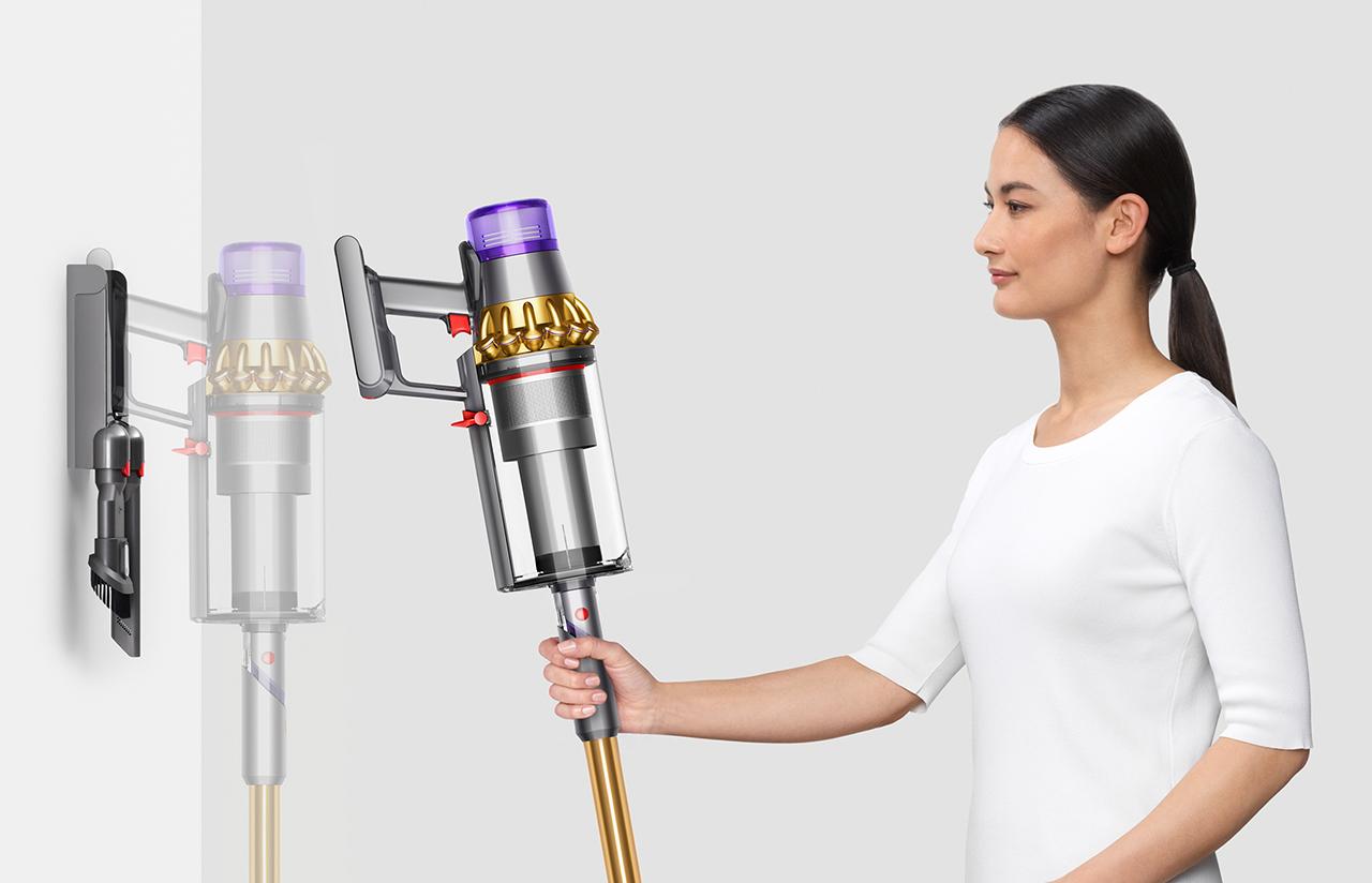 Woman placing Dyson Outsize Absolute vacuum into wall charging dock