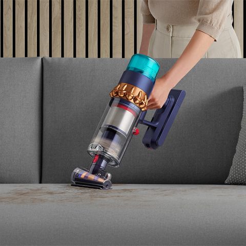 Woman vacuuming pet hair from a sofa, with the Dyson Hair screw tool. Woman vacuuming pet hair from a sofa, with the Dyson Hair screw tool.