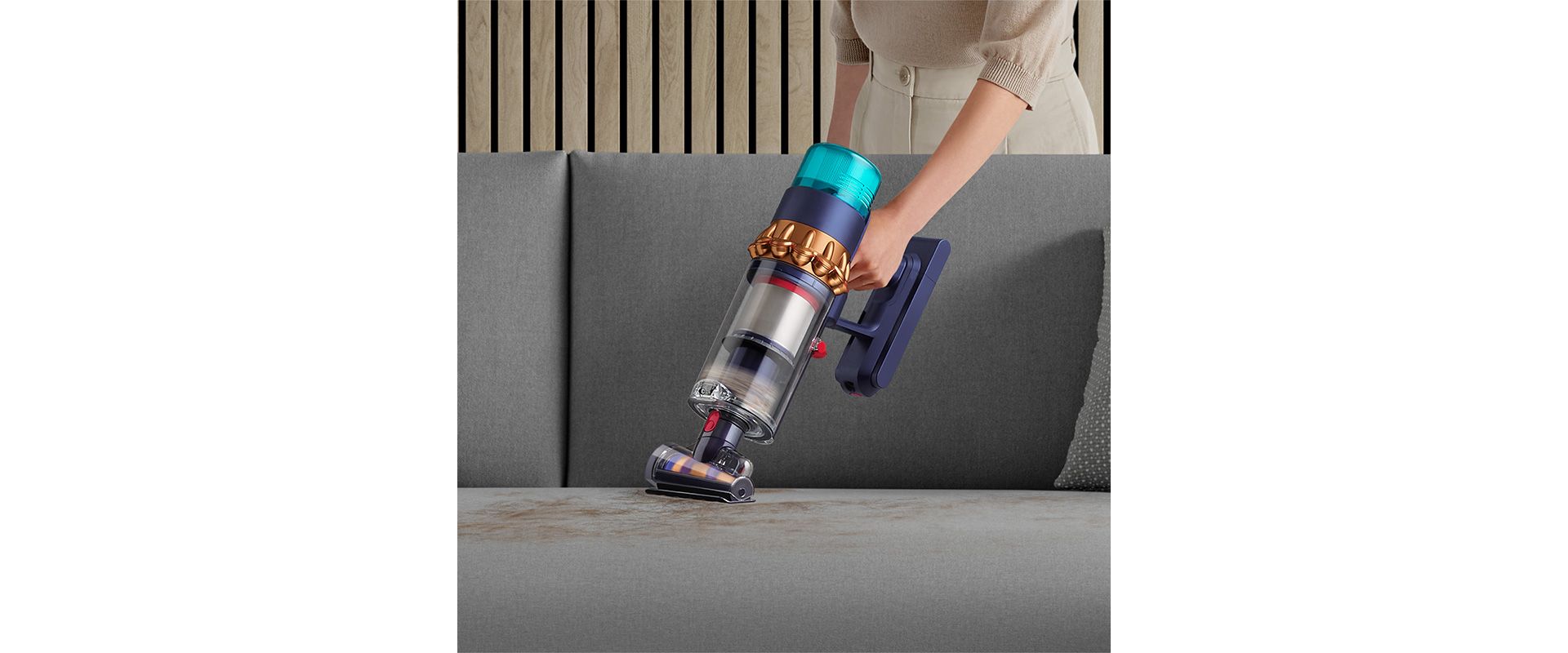 Woman vacuuming pet hair from a sofa, with the Dyson Hair screw tool.