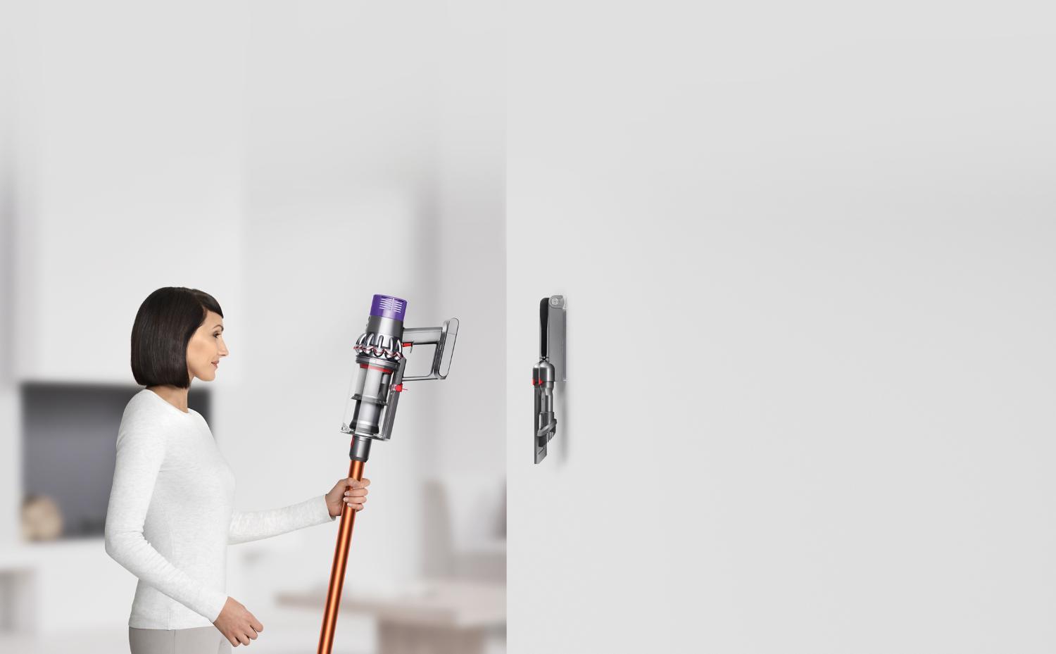 Woman placing Dyson Cyclone V10™ vacuum into wall dock