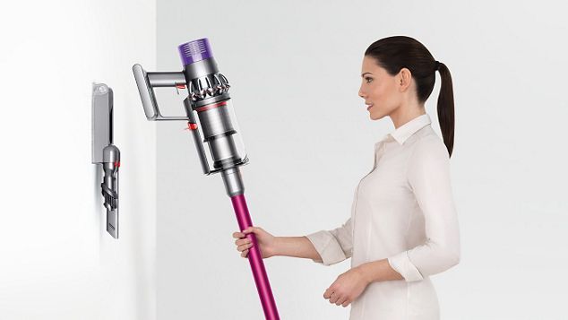 Eine Frau setzt den Dyson Cyclone V10 ordentlich in die Wandhalterung mit Ladefunktion ein