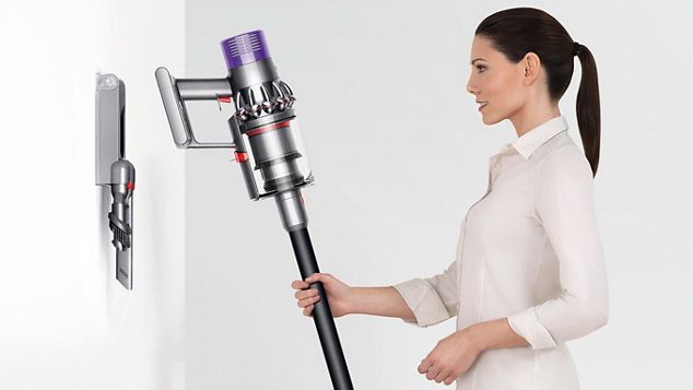 壁面の充電ドックにDyson V10クリーナーを収める女性