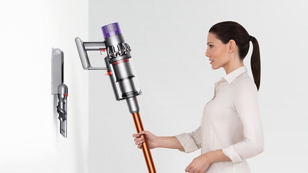 dyson-cyclone-v10-vacuum-wall-mounted-dock Donna che ripone ordinatamente Dyson Cyclone V10 nella stazione di ricarica