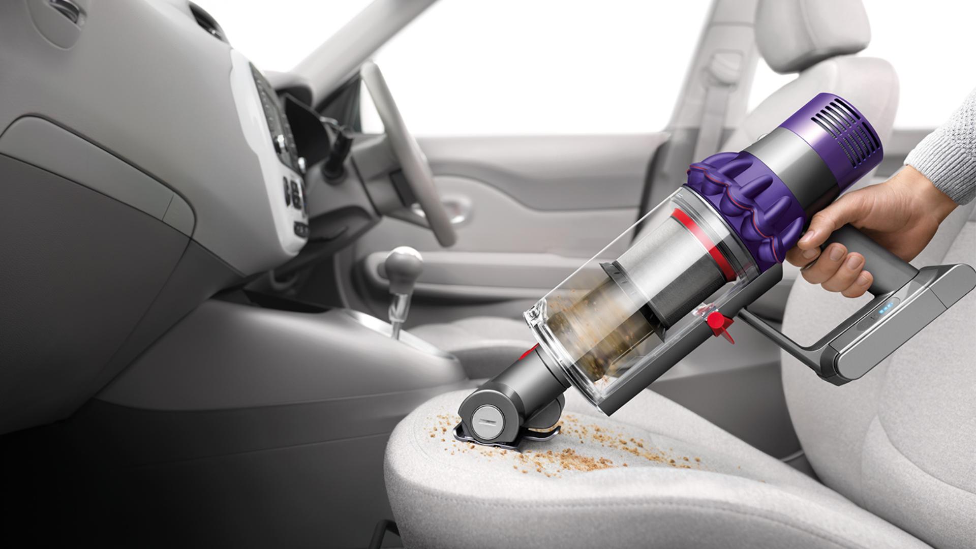 Dyson Cyclone V10 vacuum cleaner being used a handheld to clean car interior