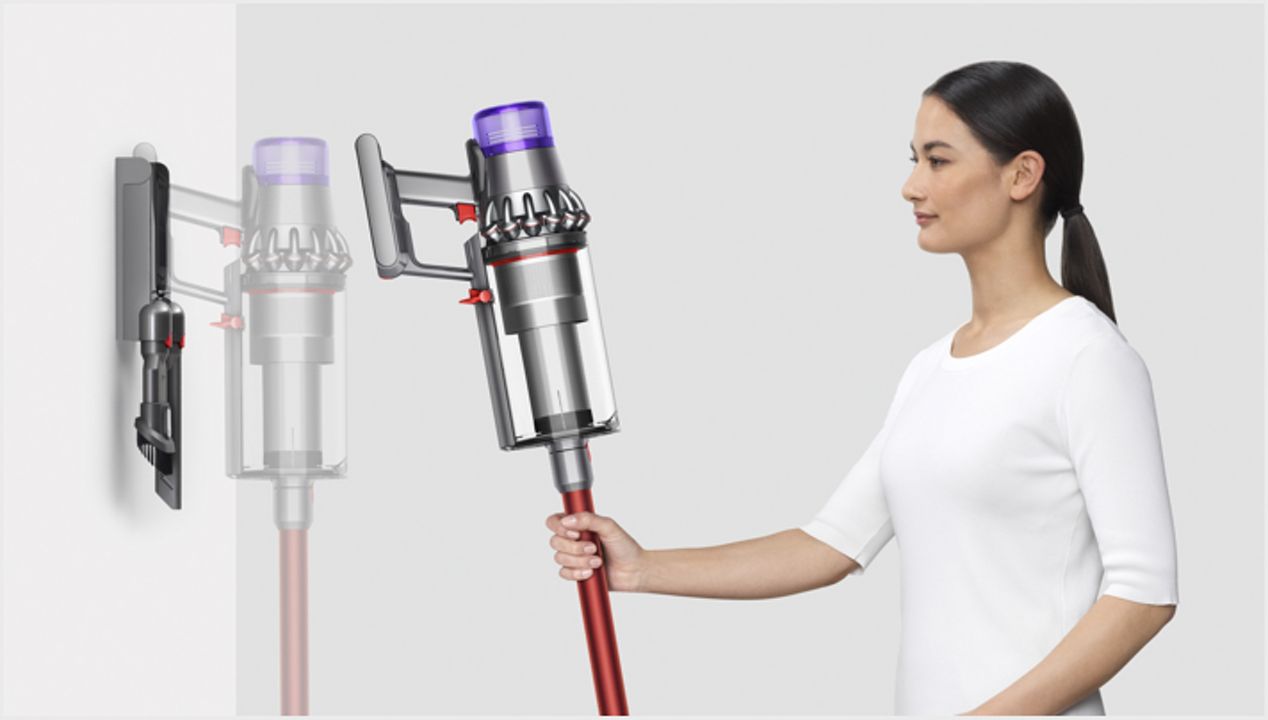 Woman placing Dyson Outsize vacuum into wall charging dock