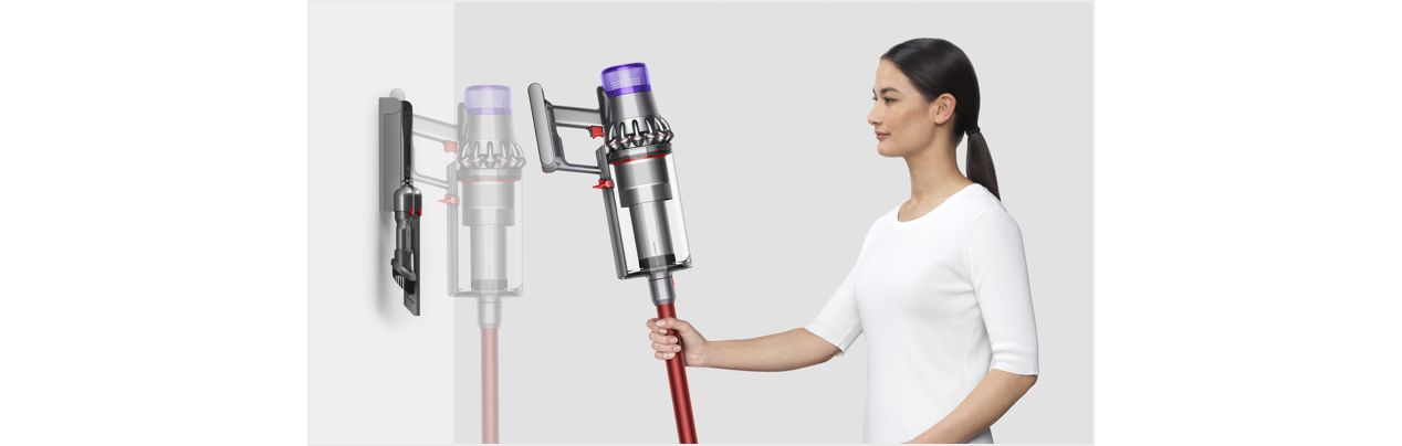 Woman placing Dyson Outsize vacuum into wall charging dock