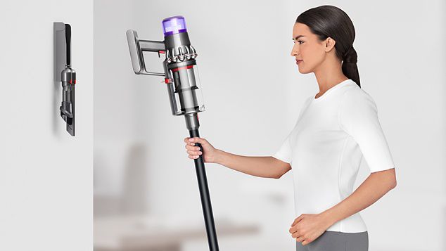 Woman placing Dyson V11™ vacuum into wall charging dock