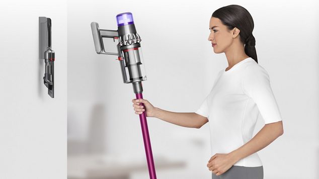 Woman placing a Dyson V11 vacuum on its wall-mounted docking station