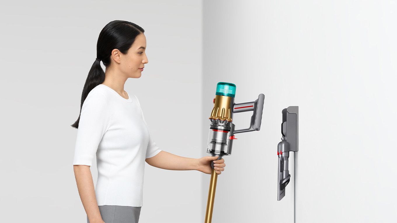 Woman placing Dyson vacuum into the wall dock.