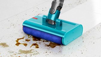 Dyson Submarine wet roller head approaches debris and liquids on a stone floor leaving behind a clean sheen.