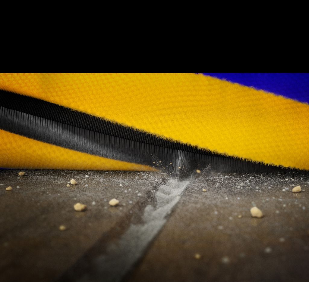  Extreme closeup of the brush bar as it rotates and the carbon fibre filament scoops up dust from a groove on a hard floor.