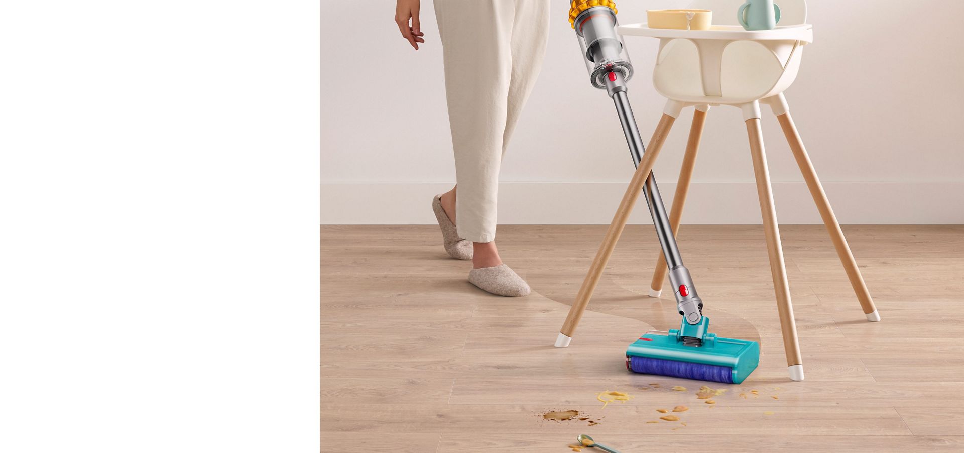Dyson V15s Detect Submarine wet roller head angled in between a high chairs legs clearing spilt food and drink off a laminate floor.