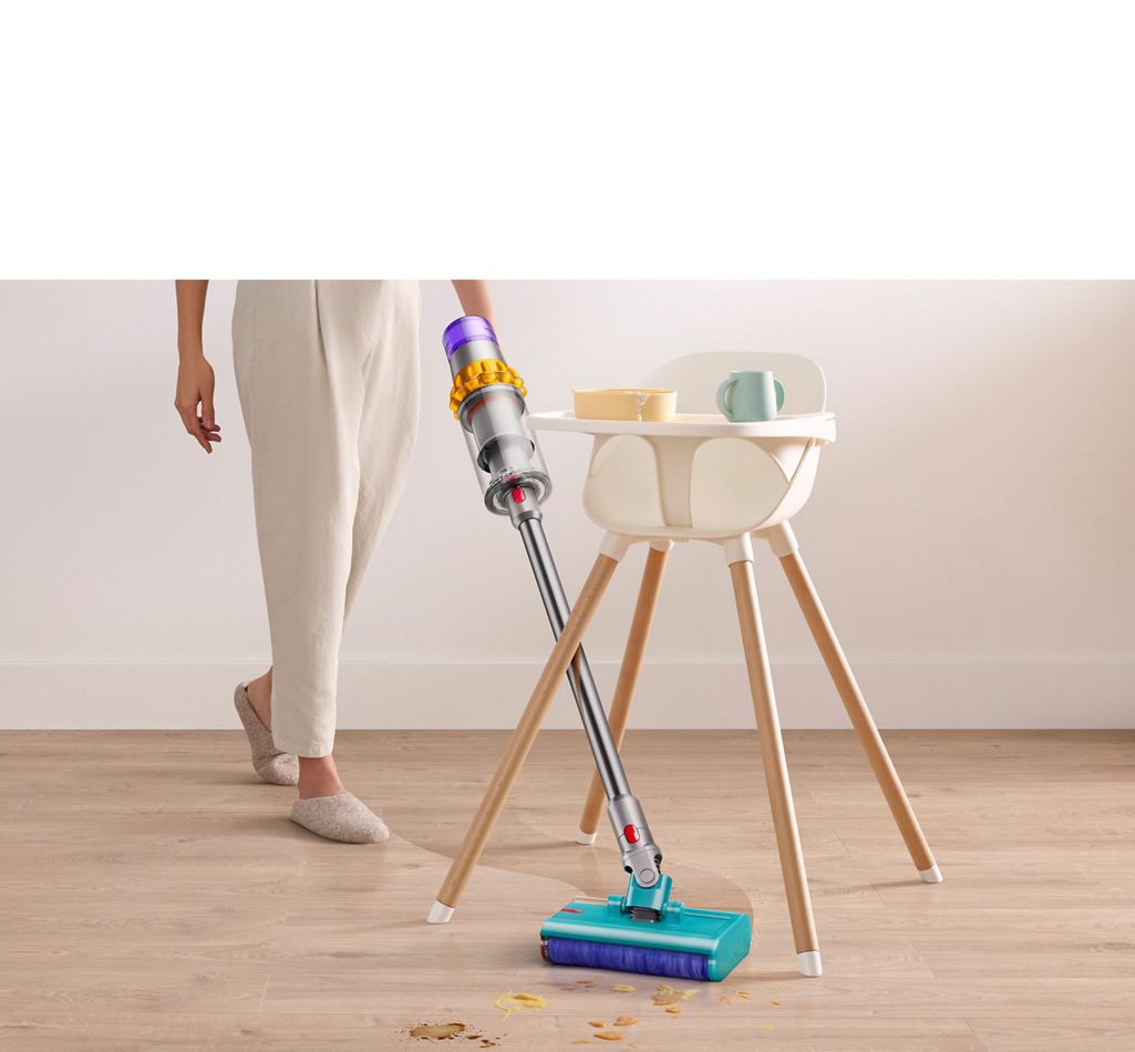 Dyson V15s Detect Submarine wet roller head angled in between a high chairs legs clearing spilt food and drink off a laminate floor.