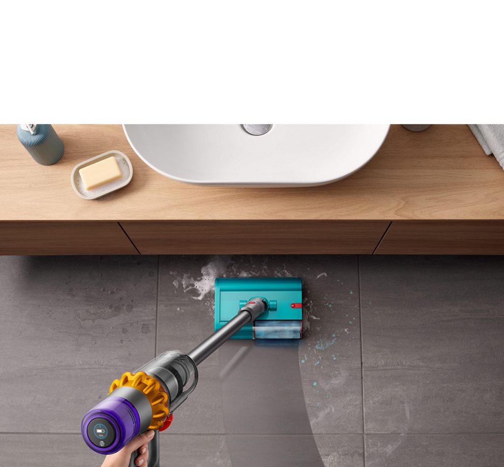 Dyson V15s Detect Submarine wet roller head cleaning a tiled bathroom floor from soapy water and toothpaste with a basin located to the front.