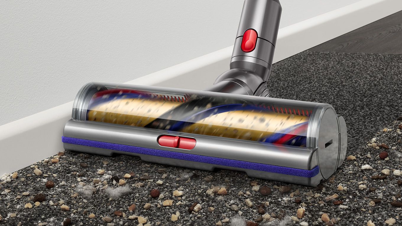 Digital Motorbar cleaner head leaves behind a clean streak along a dark carpet littered in dirt and debris up against the skirting board.