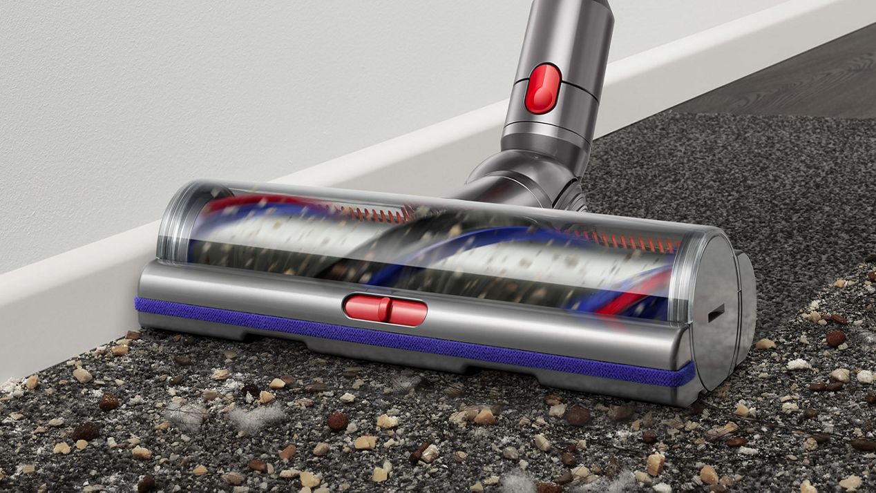 Digital Motorbar cleaner head leaves behind a clean streak along a dark carpet littered in dirt and debris up against the skirting board.