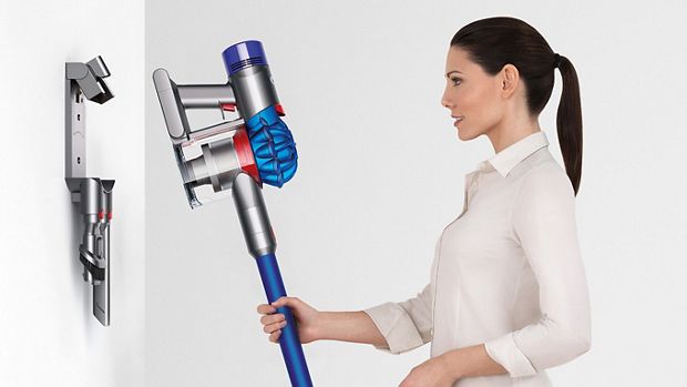 Kobieta odkładająca odkurzacz Dyson do ściennej stacji dokującej