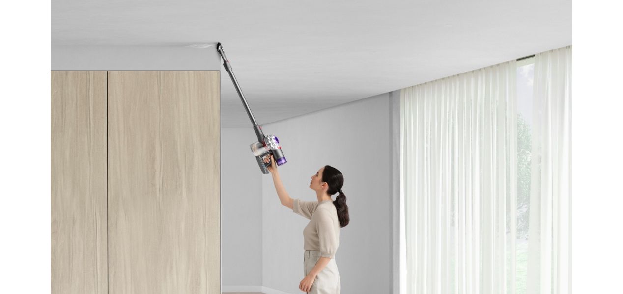 Woman cleaning up high with Dyson V8 vacuum