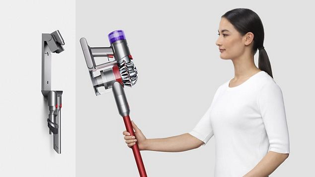 Una signora che ripone l'aspirapolvere Dyson V8™ nella stazione di ricarica