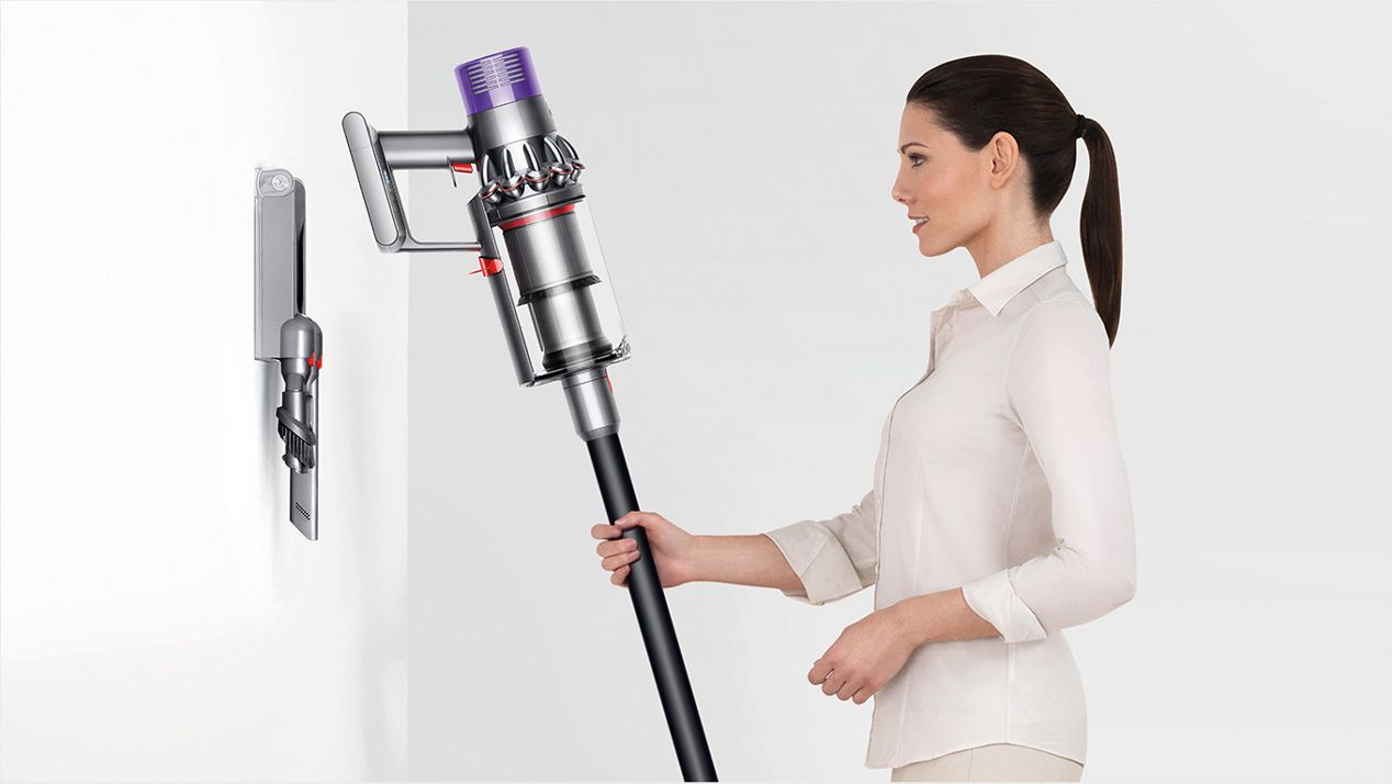 A woman putting the Dyson Cyclone V10 into its docking station