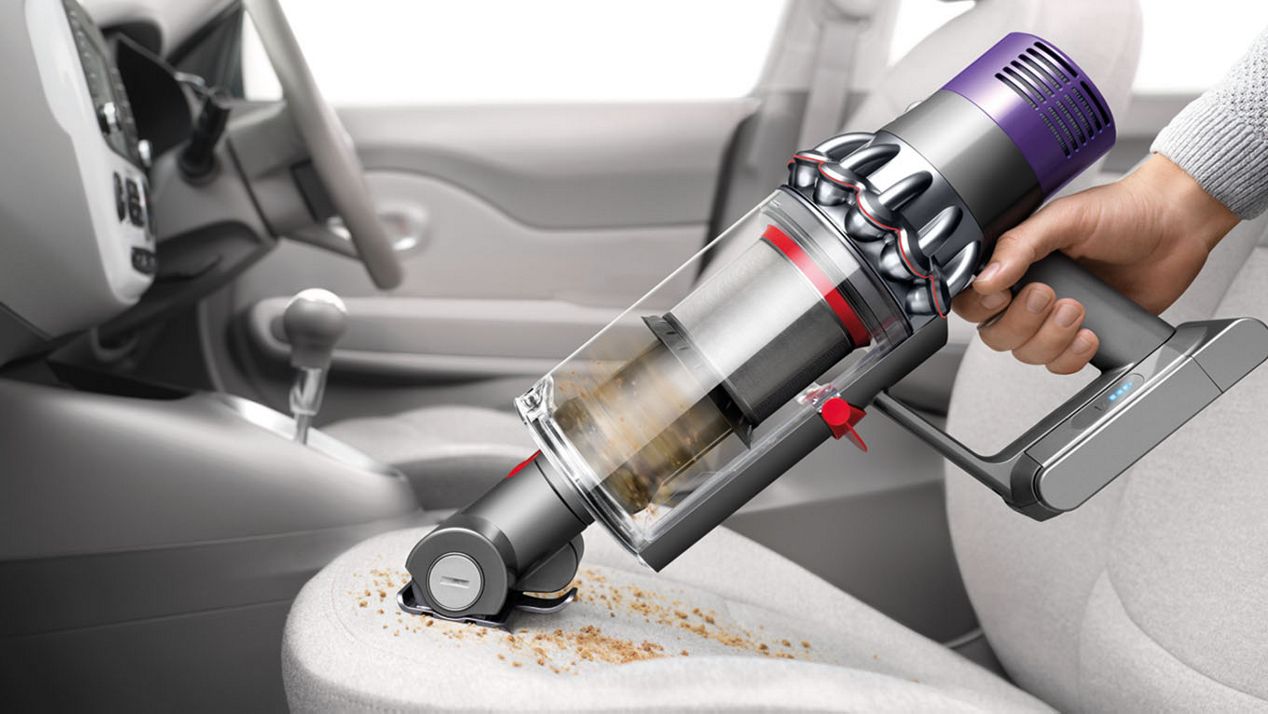 The Dyson Cyclone V10 used as a hand vacuum cleaner for cleaning the interior of a car
