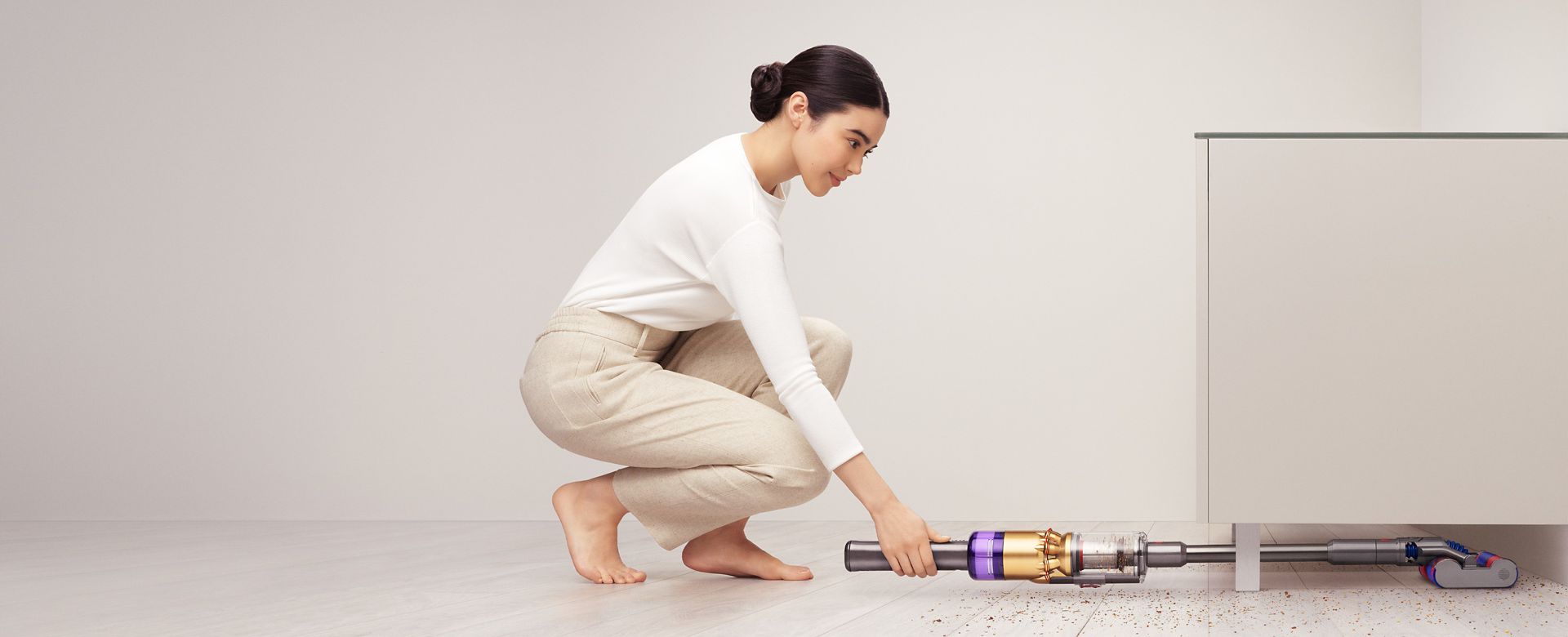 戸棚の下をDyson Omni-glideで掃除する女性。