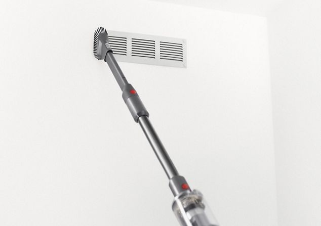 Dyson Omni-glide™ Staubsauger bei der Reinigung einer Entlüftungsöffnung in der Wand im Handstaubsaugermodus.