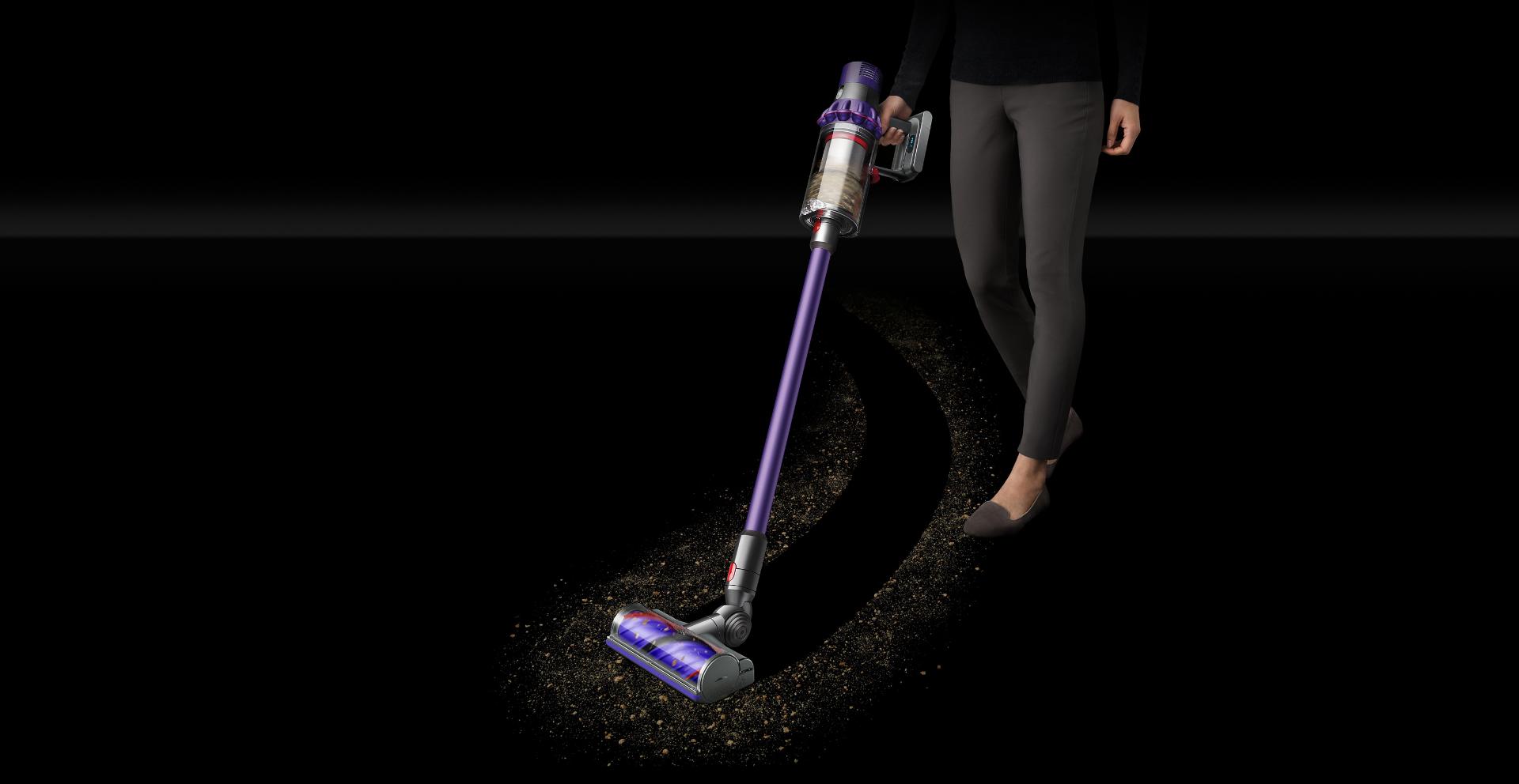 Woman collects dirt using Dyson Cyclone V10 vacuum cleaner.