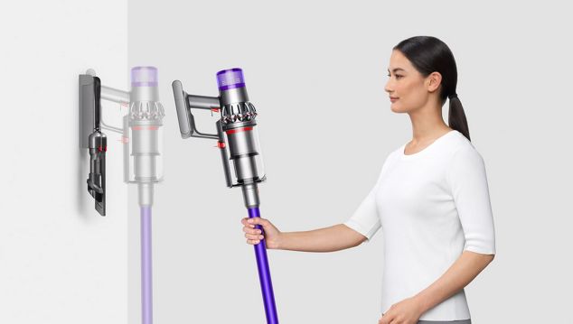 Woman placing a Dyson V11 vacuum on its wall-mounted docking station