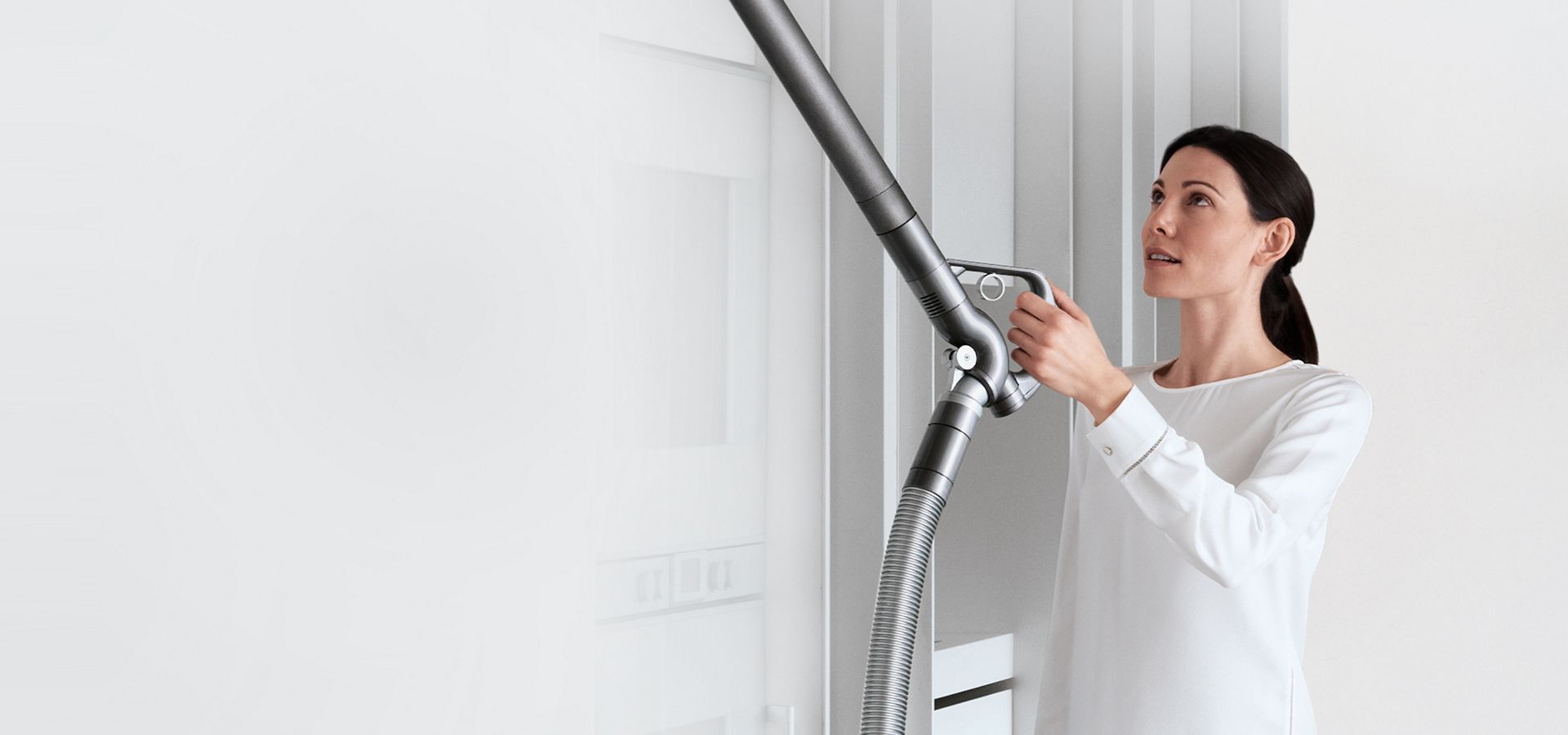 Une femme utilisant le tube articulé du Dyson Big Ball pour nettoyer une surface en hauteur.