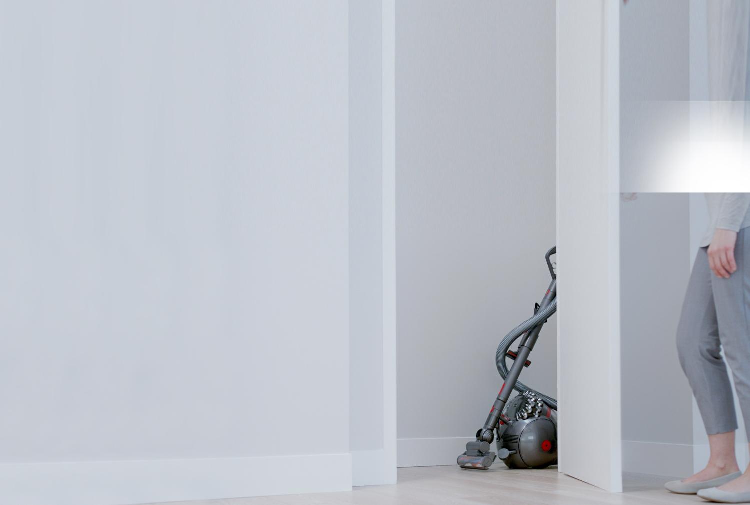 Femme s’approchant de l’aspirateur Dyson Cinetic Big Ball dans un coin.